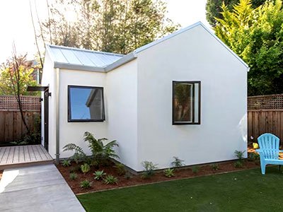 Exterior view of a small Accessory Dwelling Unit (ADU) with a pristine white exterior. The simplicity of the white facade offers a clean and modern appearance, enhancing the visual appeal of the structure. This minimalistic design approach creates a fresh and inviting atmosphere, ideal for a variety of settings and architectural styles.
