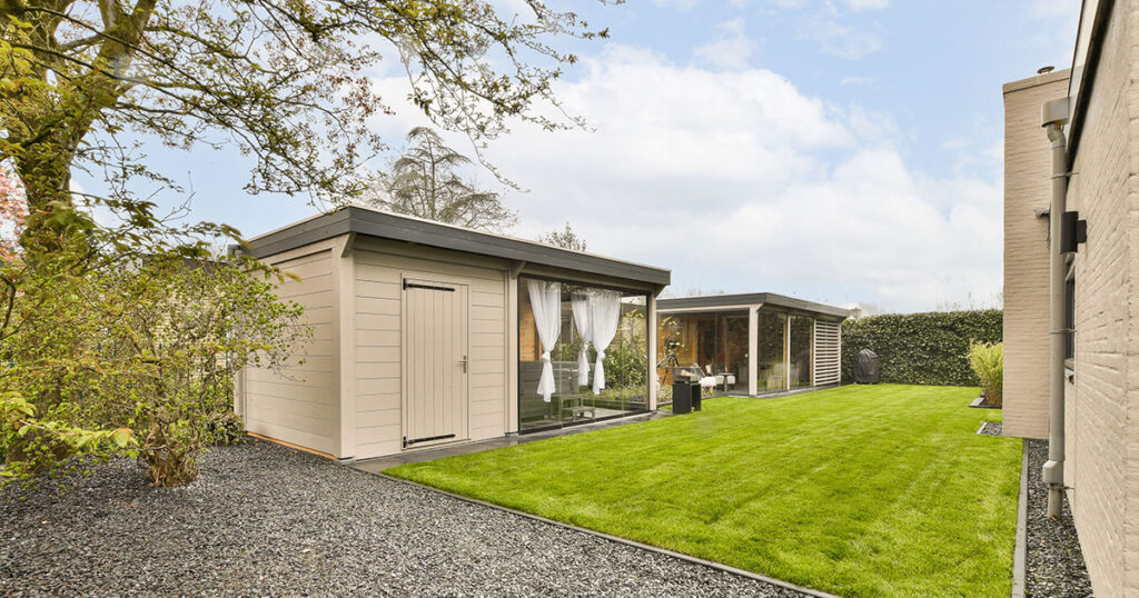 a backyard area with a shed and green grass in the yard is surrounded by trees, shrubs and bushes on both sides