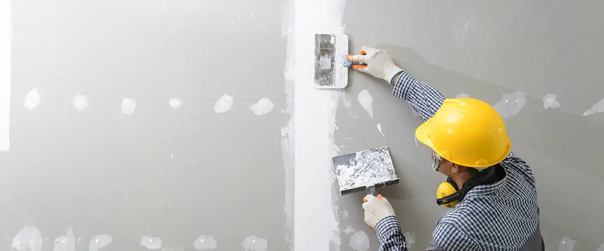 Worker performing drywall repair in Downey