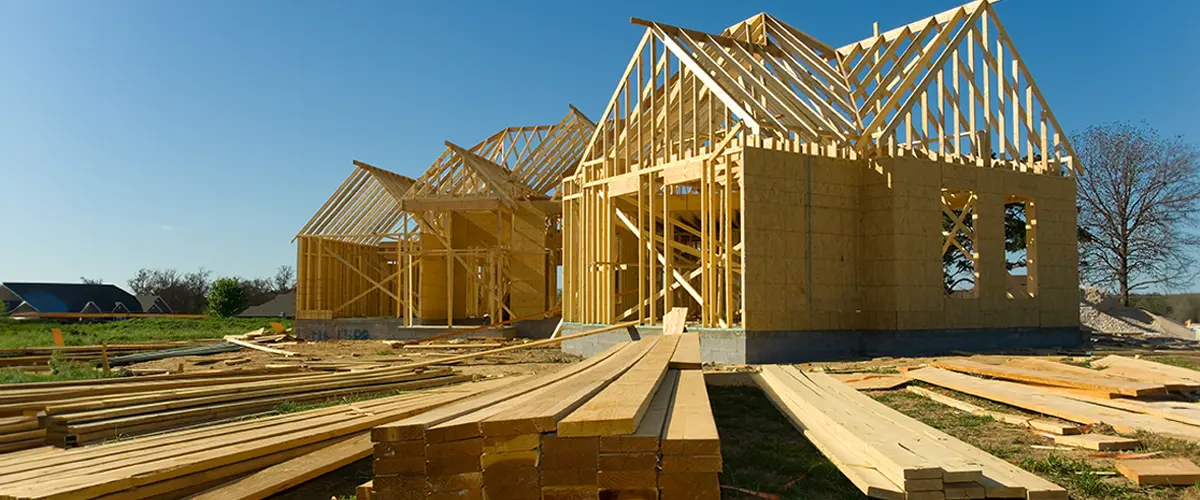 Wooden house framing for home building in Cerritos on a sunny day with blue sky.