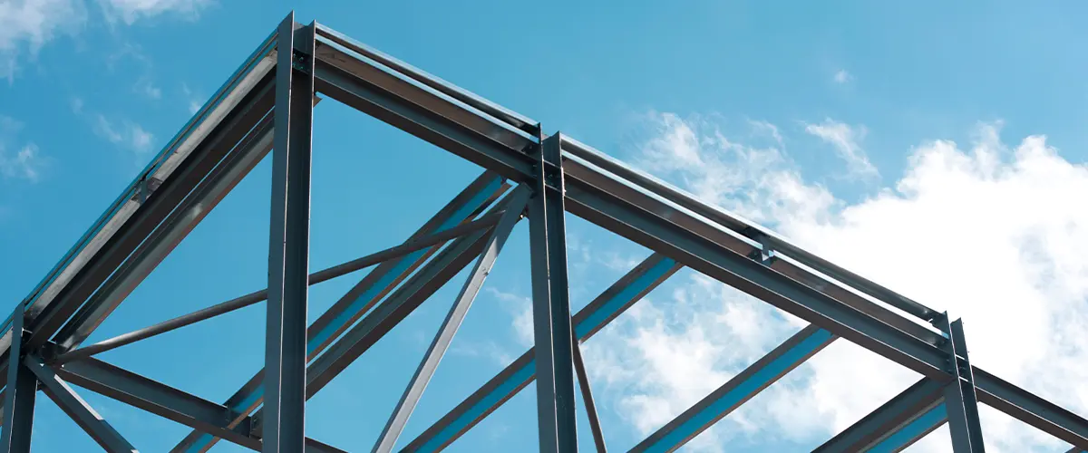 Steel building framework under construction against a clear blue sky, emphasizing structural integrity and durability.