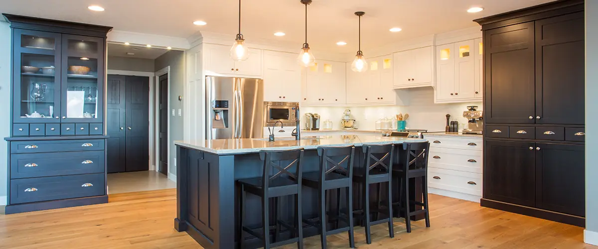 Transitional kitchen with dark cabinetry, light countertops, and a large kitchen island with bar stools and pendant lighting.