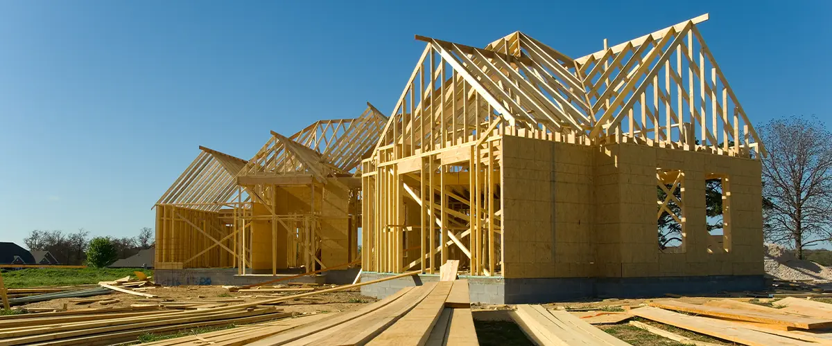 Wooden house framing construction under clear blue sky for a new residential home build.