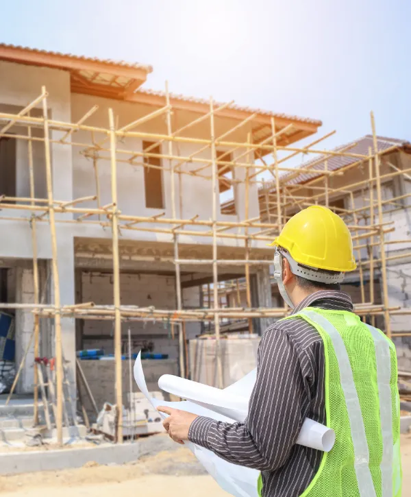 a construction engineer or site manager holding blueprints and overseeing residential construction work