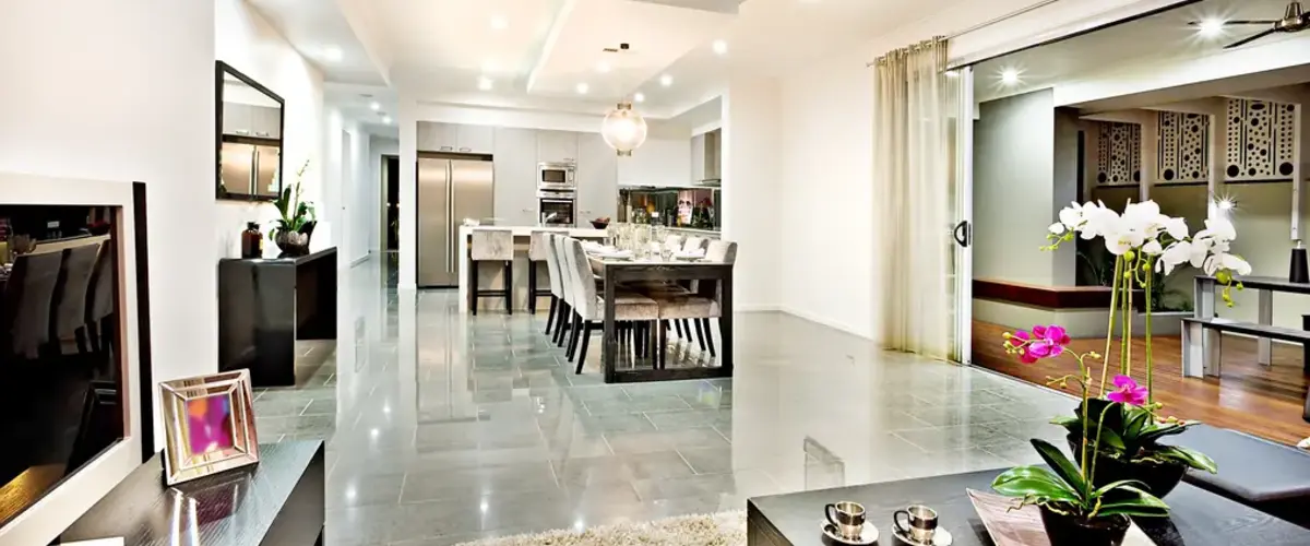 A spacious modern kitchen and dining room with grey polished tile floors, stainless steel appliances, and large sliding glass doors leading to a patio.