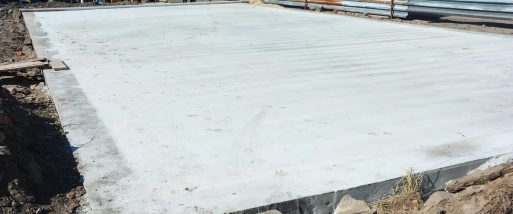 A smooth, freshly poured monolithic slab concrete foundation showing the integrated footing and floor surface.