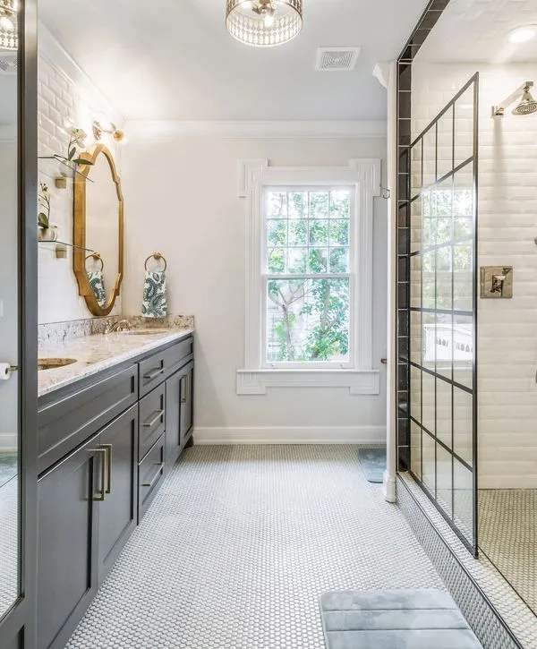 A modern bathroom renovation with a dark grey vanity, gold hardware, and mosaic tile flooring from professional bathroom remodeling companies in Norwalk, CA.